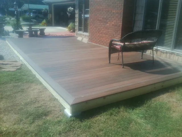 New wood deck and wicker chair beside a brick house in Little Chute