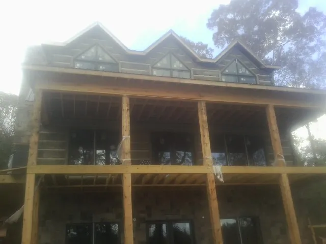Dormers and porch framing on a large log home under construction — Roof Coating work by our crew in Little Chute
