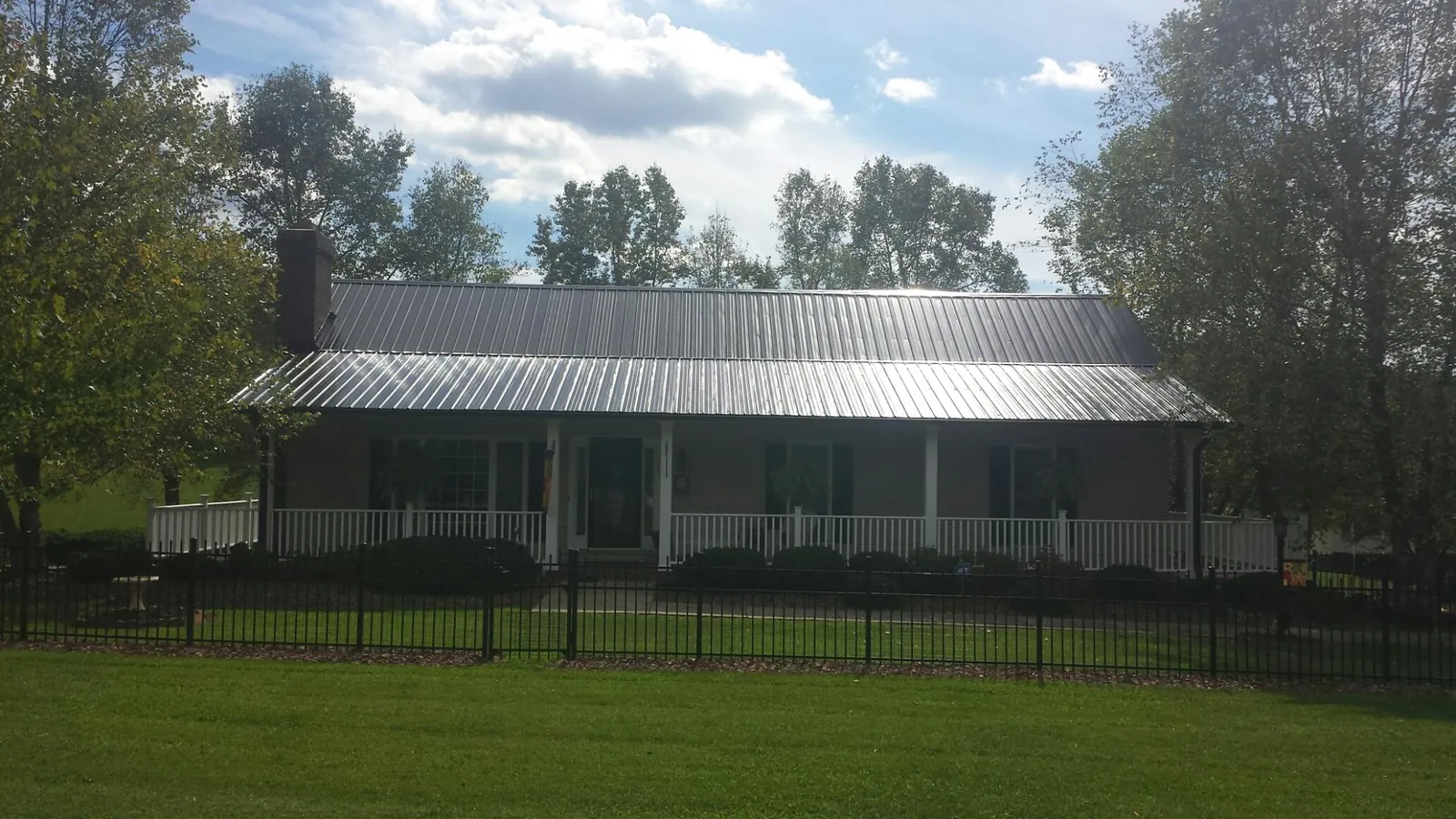 Gray metal roof on a brick ranch with a full width front porch — Gutter Guard Installation work by our crew in Little Chute