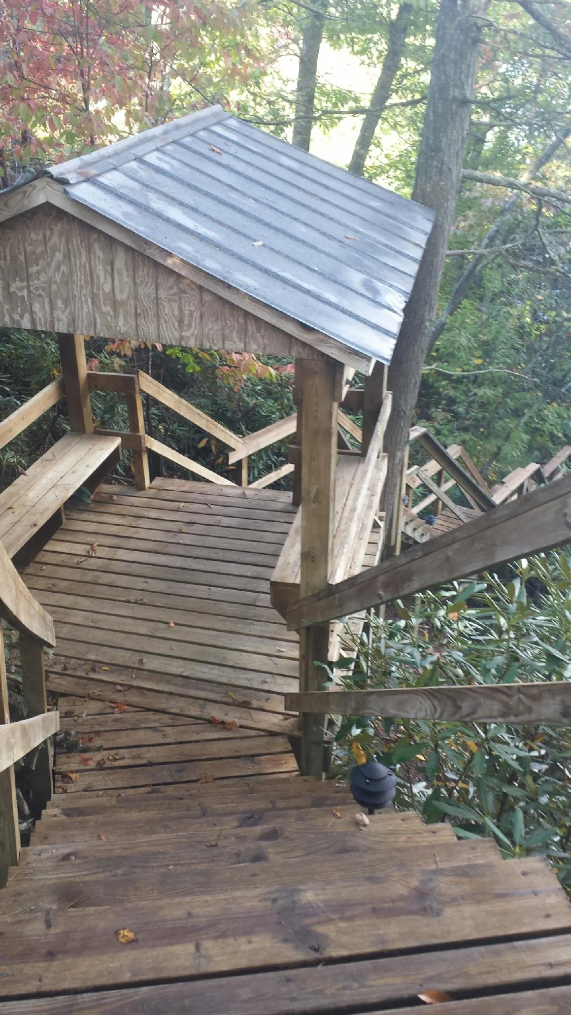 Metal roofed shelter over wooden steps on a wooded walkway — Skylight Repair & Installation work by our crew in Little Chute