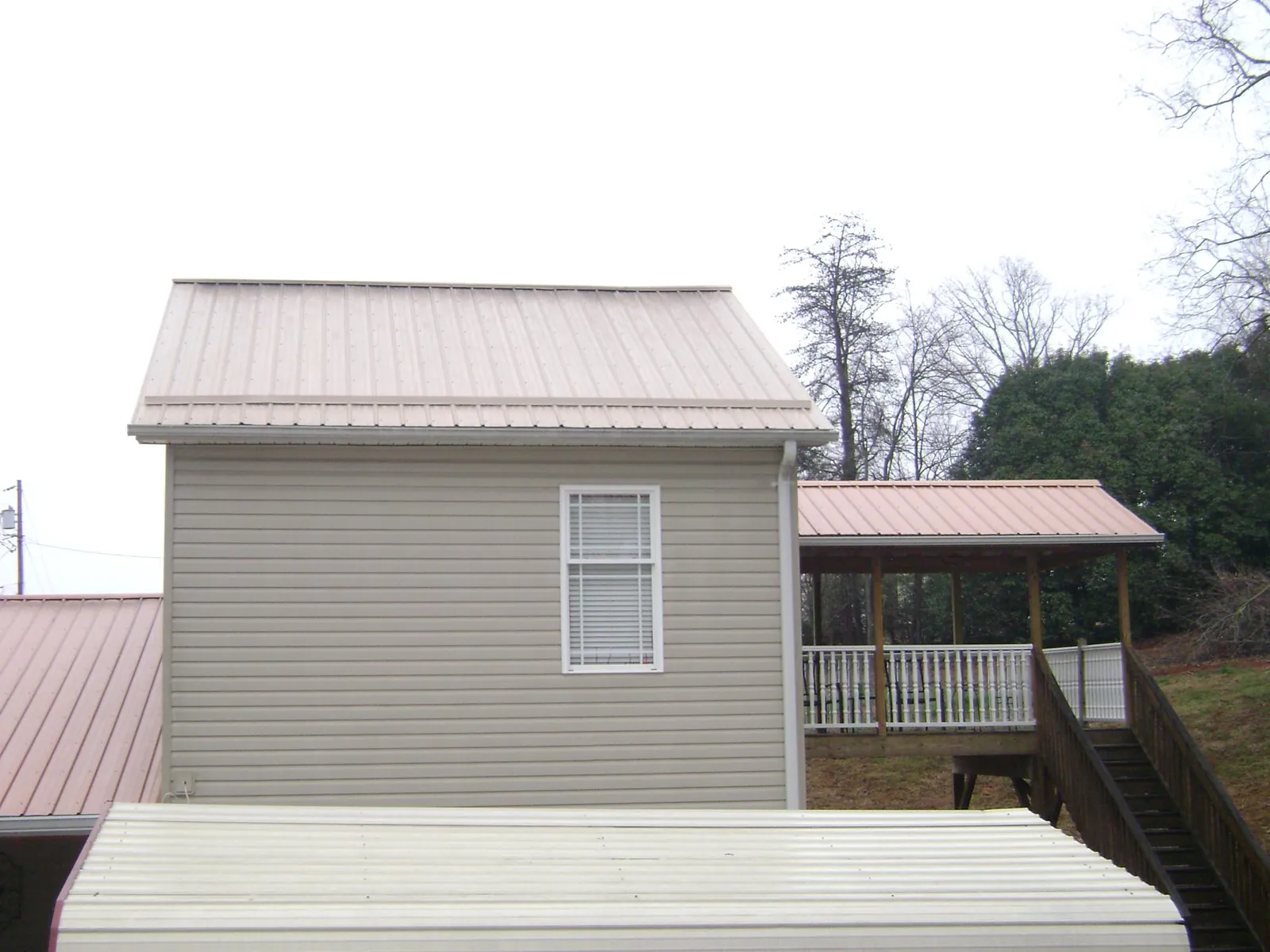 Tan metal roofs on a two story addition and attached porch, from a Roof Replacement job in Little Chute