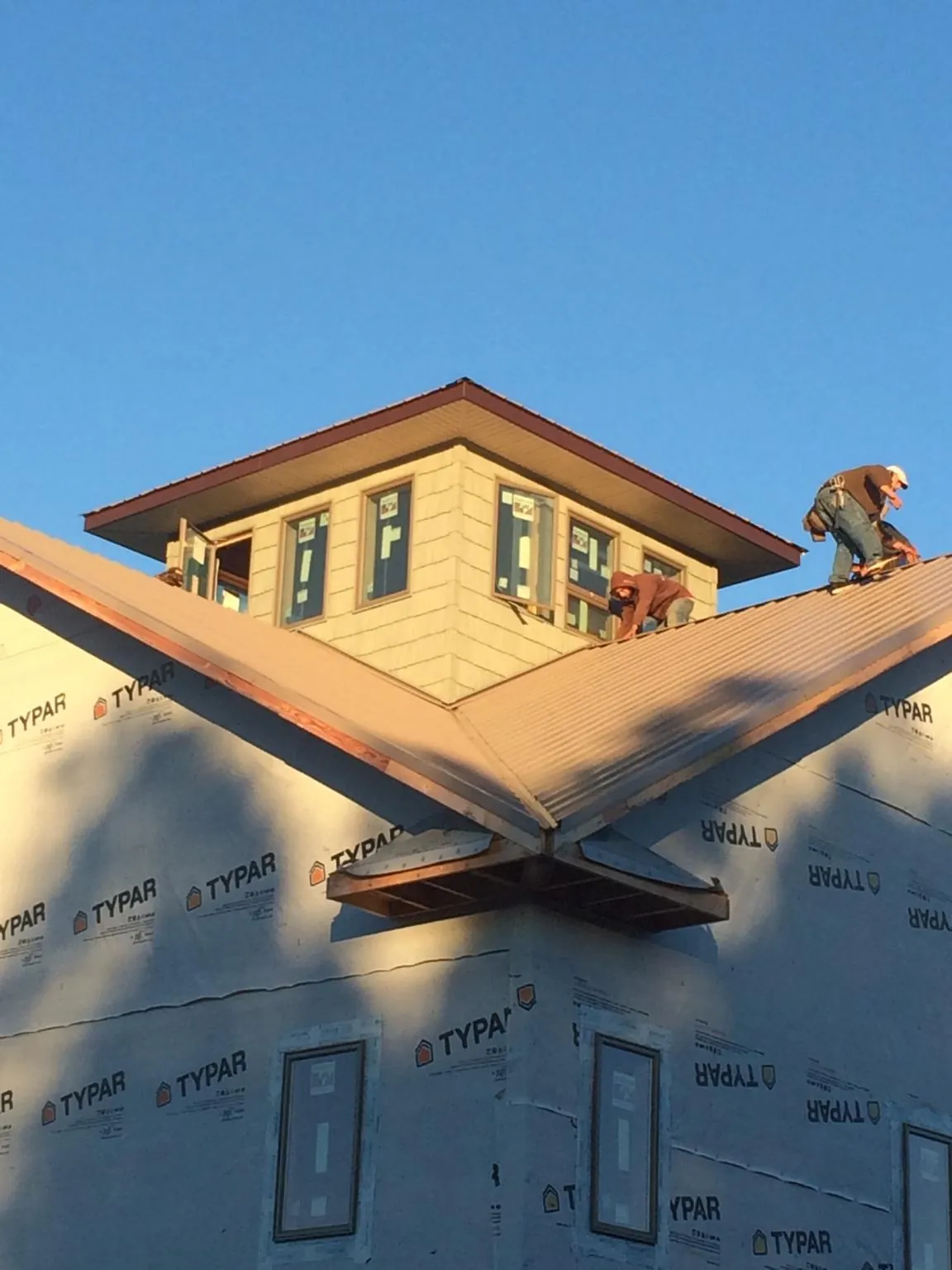 Roofers working around a rooftop cupola on a new metal roof at sunset — Roof Waterproofing in Little Chute by Roofing Brothers